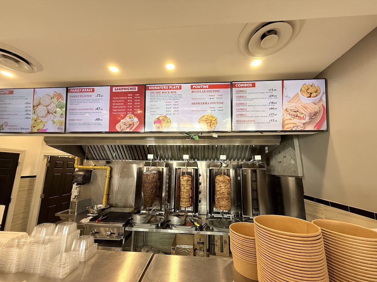 The kitchen line with shawarma spits, menu boards and stacked bowls