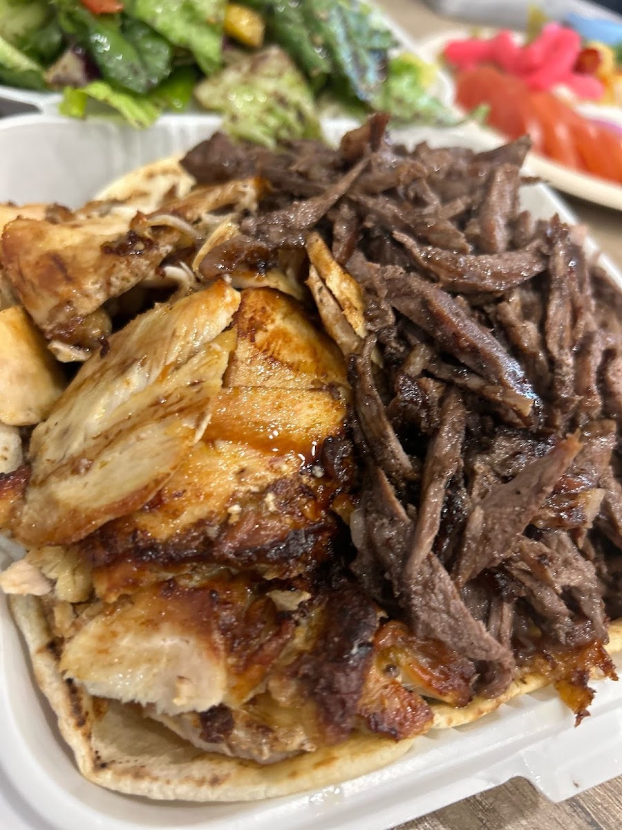 Mixed chicken and beef shawarma piled on pita in a takeout container